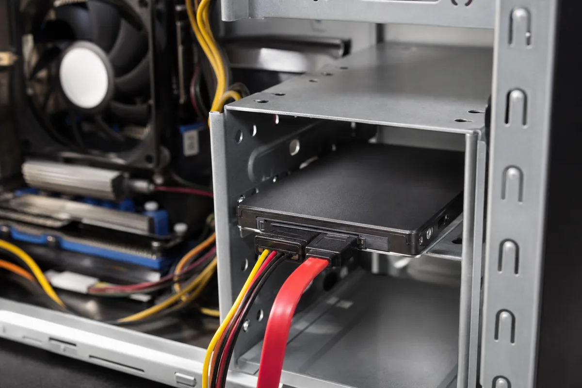 Intérieur d&rsquo;une tour d&rsquo;ordinateur ouverte avec un SSD 2,5 pouces fixé dans un rack et ses câbles SATA