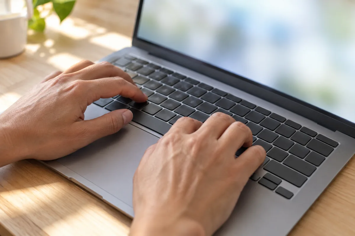 Mains sur le clavier d’un ordinateur portable ouvert sur les paramètres système flous